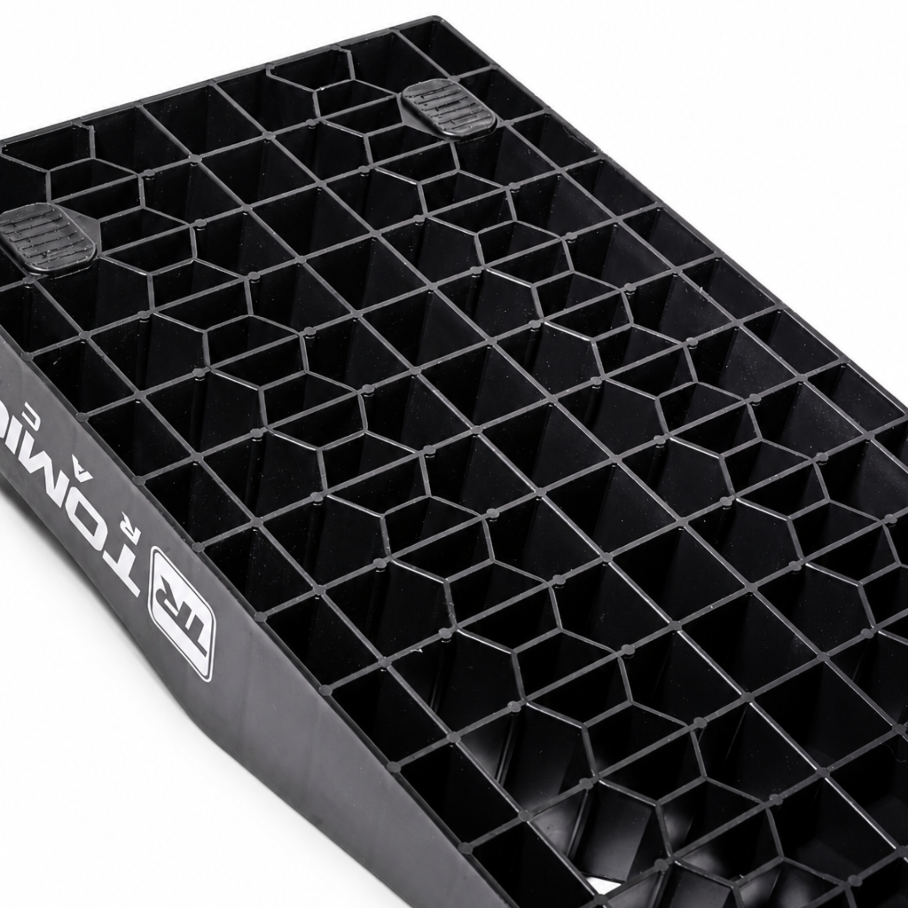 Black textured tray with geometric pattern on a white background. Tomioka Racing with rubber stands holder on the corner